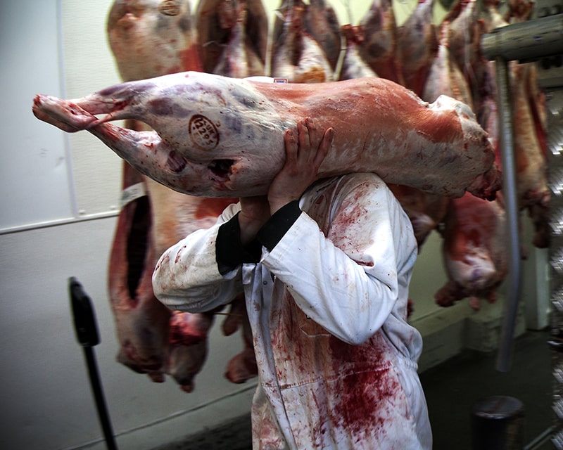 https://www.keeButcher photography of butcher covered in blood carrying a lamb carcass on his shoulder in the Keevil & Keevil Cutting Room at Smithfield Market in London