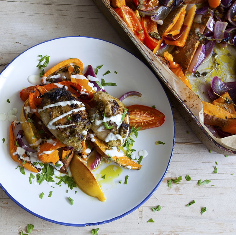 Waitrose Cook Well Basil pesto chicken, sweet potato and yellow pepper bake with herby yogurt and roasted lemon wedges on a white plate with blue edge