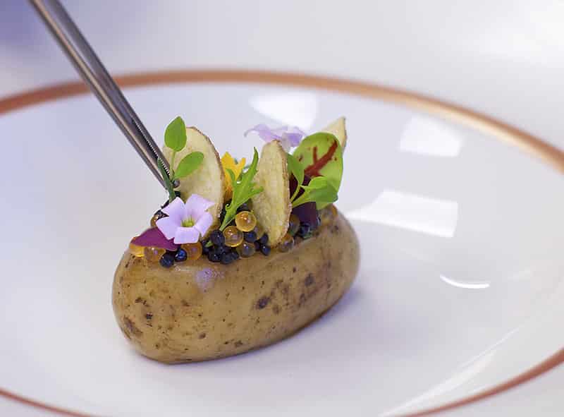 potato dish being plated with tweezers