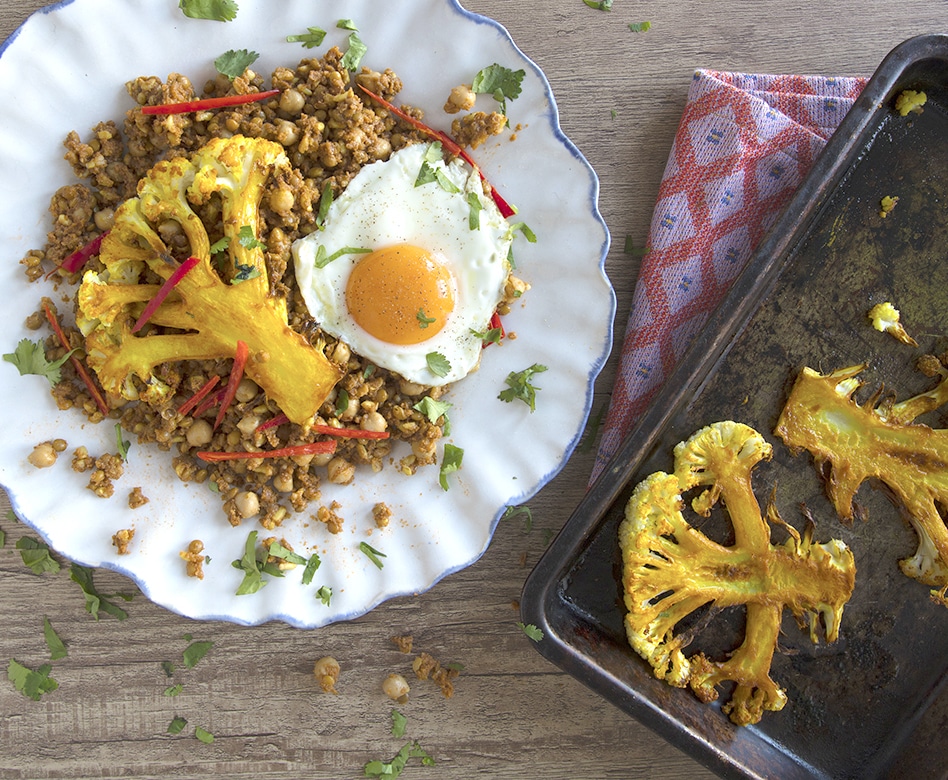 Waitrose meal kit of roast cauliflower steak with chickpeas and fried egg on a white plate against a wooden background